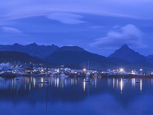 Vista nocturna de Ushuaia. Las luces iluminan el puerto y la cordillera de fondo (clickear para agrandar imagen)